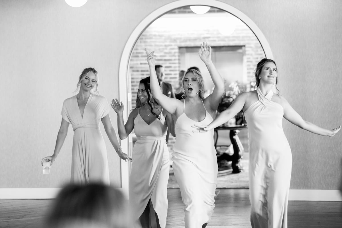Entrée dansante de la mariée et de ses demoiselles d'honneur, bras levés, en noir et blanc