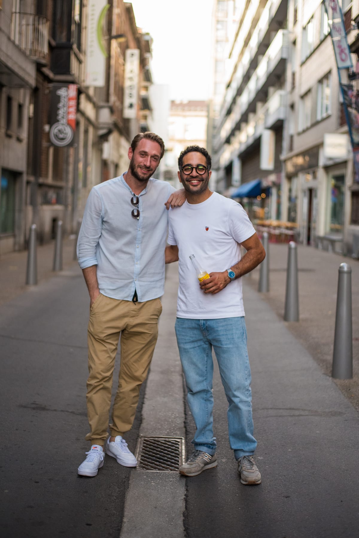 Deux amis debout au milieu d'une rue commerçante déserte au soleil couchant